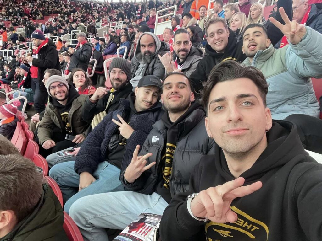 Arsenal Thessaloniki supporters take a group selfie in the stands at Emirates Stadium during the Arsenal–Brentford match in February 2023.